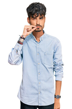 Young hispanic man wearing casual clothes mouth and lips shut as zip with fingers. secret and silent, taboo talking
