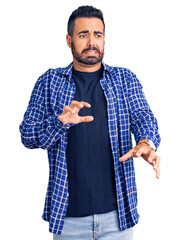 Young hispanic man wearing casual clothes disgusted expression, displeased and fearful doing...