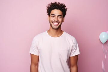 Fototapeta na wymiar Portrait of a handsome young man smiling and looking at camera against pink background