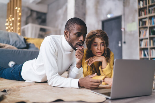 Thoughtful couple engaged with laptop in their new home, focus and planning amidst the warm, inviting ambiance of their modern living space. Shocked man check online banking app on computer