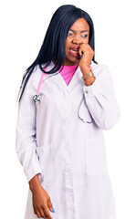 Young african american woman wearing doctor stethoscope looking stressed and nervous with hands on mouth biting nails. anxiety problem.