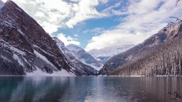 Mountain and lake scenery in cloudy blue sky day. clouds reflect on water. time lapse natural landscape, winter time background footage b roll.  gorgeous snow on the mountain giving cold vibes. 
