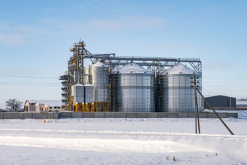 Obraz premium modern agro-processing plant for processing and silos for drying cleaning and storage of agricultural products, flour, cereals and grain in snow of winter field
