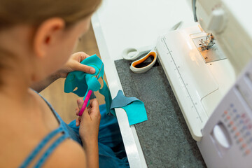 Close-up of girl working with sewing machine at home. Child girl sews clothes on sewing machine....