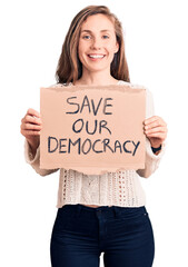 Young beautiful blonde woman holding save our democracy banner looking positive and happy standing and smiling with a confident smile showing teeth