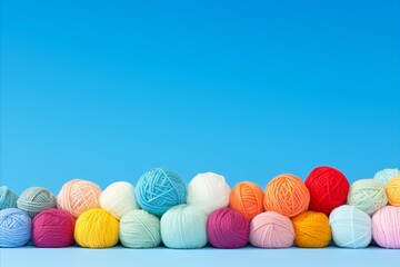Vibrant display of colorful wool yarn balls on solid sky blue background with ample space for text