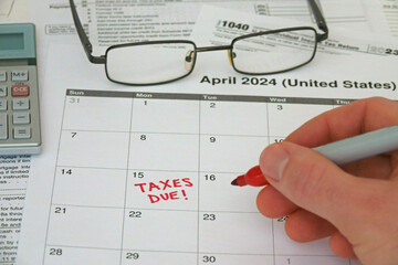 TAXES DUE! is shown written on a calendar by hand. The Internal Revenue Service IRS deadline in the USA for calendar year 2023 filing is April 15, 2024.