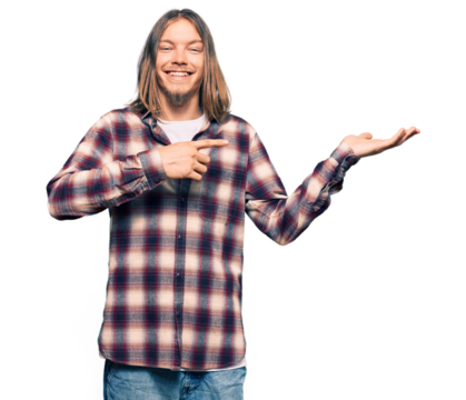 Handsome caucasian man with long hair wearing hipster shirt amazed and smiling to the camera while presenting with hand and pointing with finger. - Powered by Adobe
