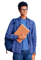 Young african american man wearing student backpack holding book smiling looking to the side and staring away thinking.