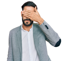 Young hispanic man wearing business clothes covering eyes with hand, looking serious and sad. sightless, hiding and rejection concept
