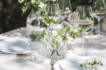 Romantic elegant luxury wedding table decor with white fresh spring blooming cherry apple tree flowers. Glass, candles, floral decoration for special marriage holiday event. No plastic zero waste