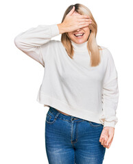 Young caucasian woman wearing casual winter sweater smiling and laughing with hand on face covering eyes for surprise. blind concept.