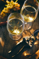 Top view of two glasses of white wine on a barrel with yellow grape and secateurs