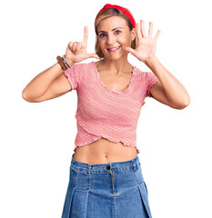 Young blonde woman wearing casual clothes and diadem showing and pointing up with fingers number seven while smiling confident and happy.