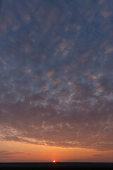 Landscape with bloody sunset. Panorama. Tragic gloomy sky. The last flashes of the sun on the storm clouds.