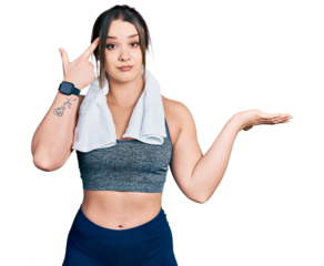 Young hispanic girl wearing sportswear and towel confused and annoyed with open palm showing copy space and pointing finger to forehead. think about it.