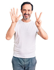 Fototapeta premium Middle age handsome man wearing casual t-shirt showing and pointing up with fingers number seven while smiling confident and happy.