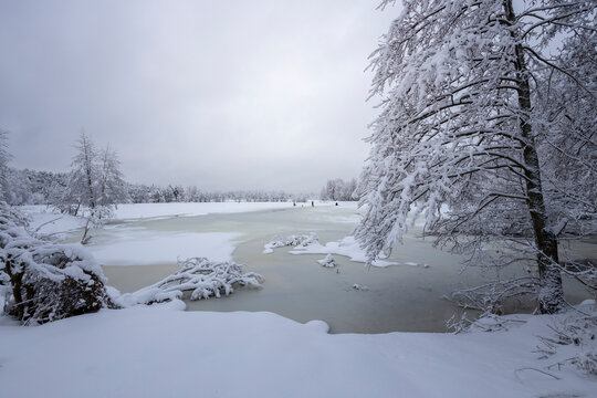 Frozen lake covered with ice and snow, Winter landscape, fishermen on the ice of the river