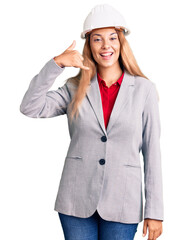 Beautiful young woman wearing architect hardhat smiling doing phone gesture with hand and fingers like talking on the telephone. communicating concepts.