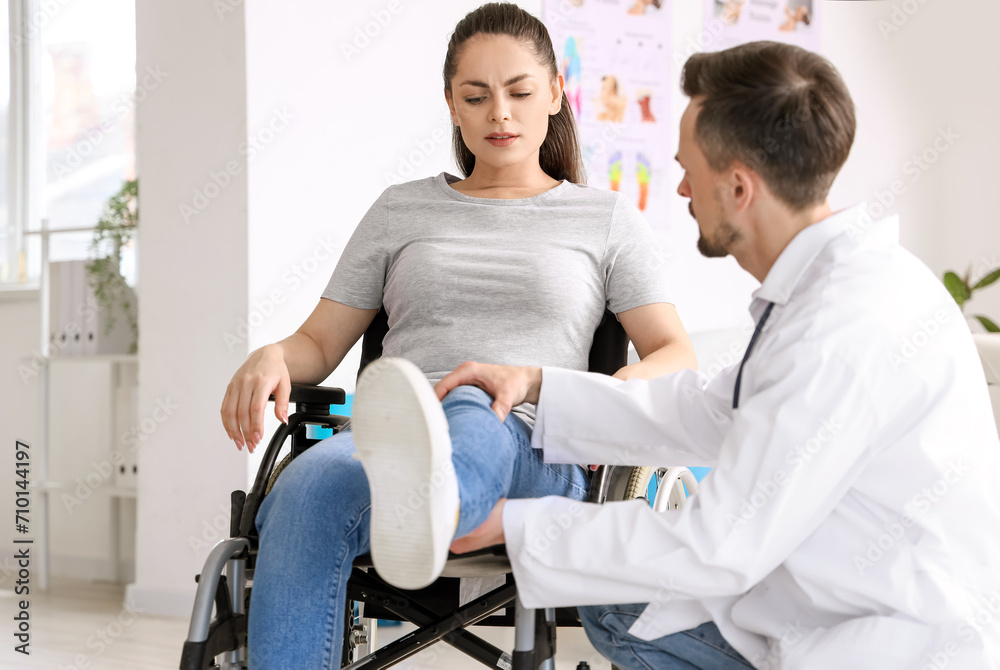 Sticker Male physiotherapist working with young woman in wheelchair at rehabilitation center