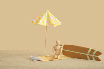 Creative composition with miniature surfboard, umbrella and wooden mannequin on sand against beige...