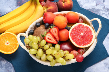 Wicker basket with different fresh fruits on blue background