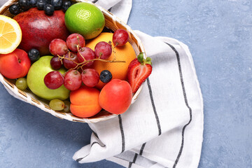 Wicker bowl with different fresh fruits on blue background
