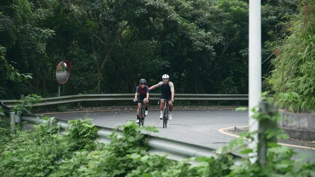 young asian couple cycling together on rural road