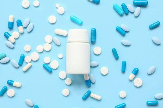 Jar with different pills on blue background