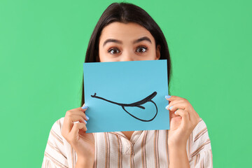 Young woman with paper smile on green background