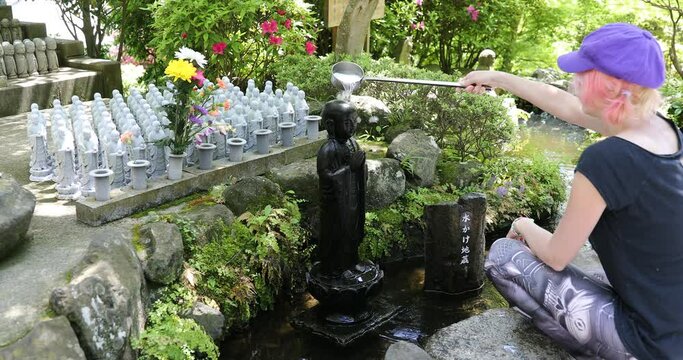 Woman worshipping at Jizo Statue. Hase-dera Temple in Kamakura, Japan. Japanese culture concept.