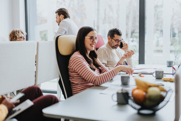 Different aged coworkers collaborate happily in a modern office lobby, using technology and teamwork to achieve successful results.