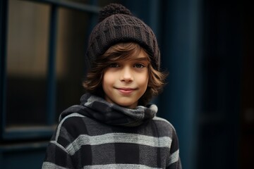 smiling boy in warm hat and scarf looking at camera on street