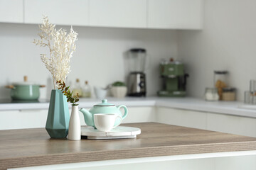 Fototapeta na wymiar Wooden table with tea set, dried flowers and eucalyptus branches in modern kitchen