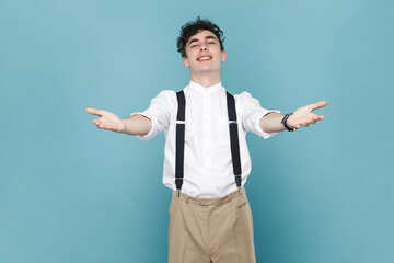 Portrait of friendly generous man wearing white shirt and suspender, raising hands up as if holding...