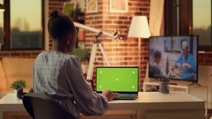 Woman looks at greenscreen on display and working on online career tasks for freelancer job, blank...