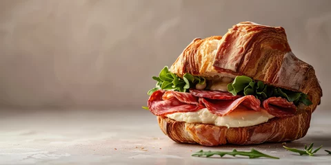 Keuken spatwand met foto Toasted Croissant Sandwich with Salami and Mozzarella. Gourmet croissant sandwich with salami, mozzarella cheese, and fresh arugula on a flat background. © dinastya