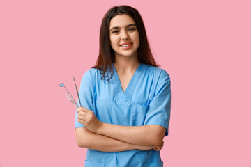 Female dentist with tools on pink background. World Dentist Day
