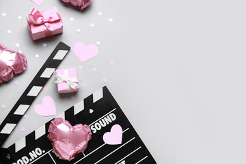 Obraz premium Movie clapper with heart shaped air balloons and gift boxes on grey background. Valentine's Day celebration
