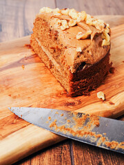 Small cake with nuts on wooden board and knife. Premium high quality dessert products. Tasty snack.