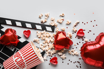 Movie clapper with bucket of popcorn and heart shaped decor on white background. Valentine's Day...