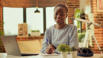Woman writing down important ideas for online freelancing career, taking notes on notebook and...