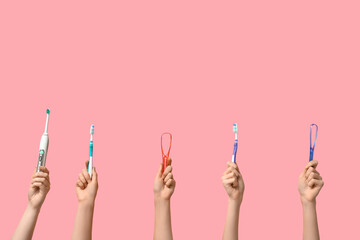 Female hands with toothbrushes and tongue scrapers on pink background - obrazy, fototapety, plakaty