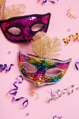 Festive face mask for carnival celebration on colored background top view, flat lay