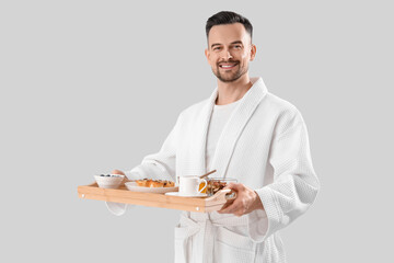 Young man with tasty breakfast on light background. Valentine's Day celebration