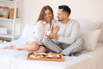Young couple having breakfast in bed on Valentine's Day