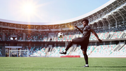 African American man playing football on the stadium field. A man runs with a soccer ball across...