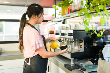 Latin young woman barista making coffee in the espresso machine