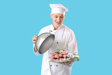 Male chef with cloche and tulips on blue background. International Women's Day celebration