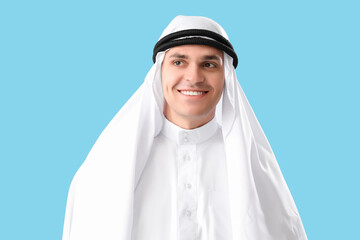 Young Muslim man on blue background, closeup. Ramadan celebration